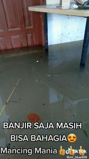 Rumah kebanjiran, pria ini justru asyik mancing di depan pintu