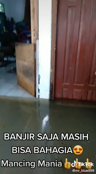 Rumah kebanjiran, pria ini justru asyik mancing di depan pintu
