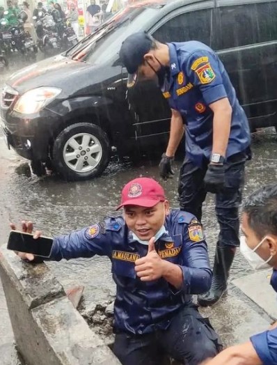 Aksi petugas damkar selamatkan HP warga di got saat hujan, bikin salut