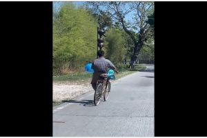 Momen lucu pria pamer skill bawa kendi di atas kepala sambil naik sepeda, aksinya random banget