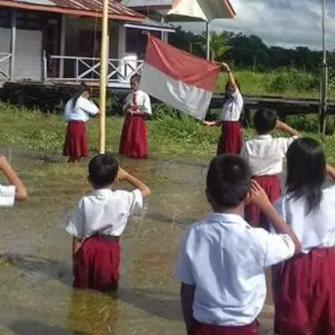 Siswa-siswa SD ini khidmat upacara bendera di tengah banjir