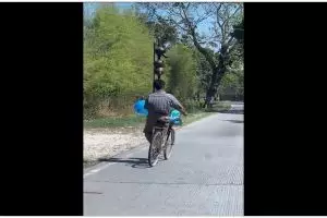 Momen lucu pria pamer skill bawa kendi di atas kepala sambil naik sepeda, aksinya random banget